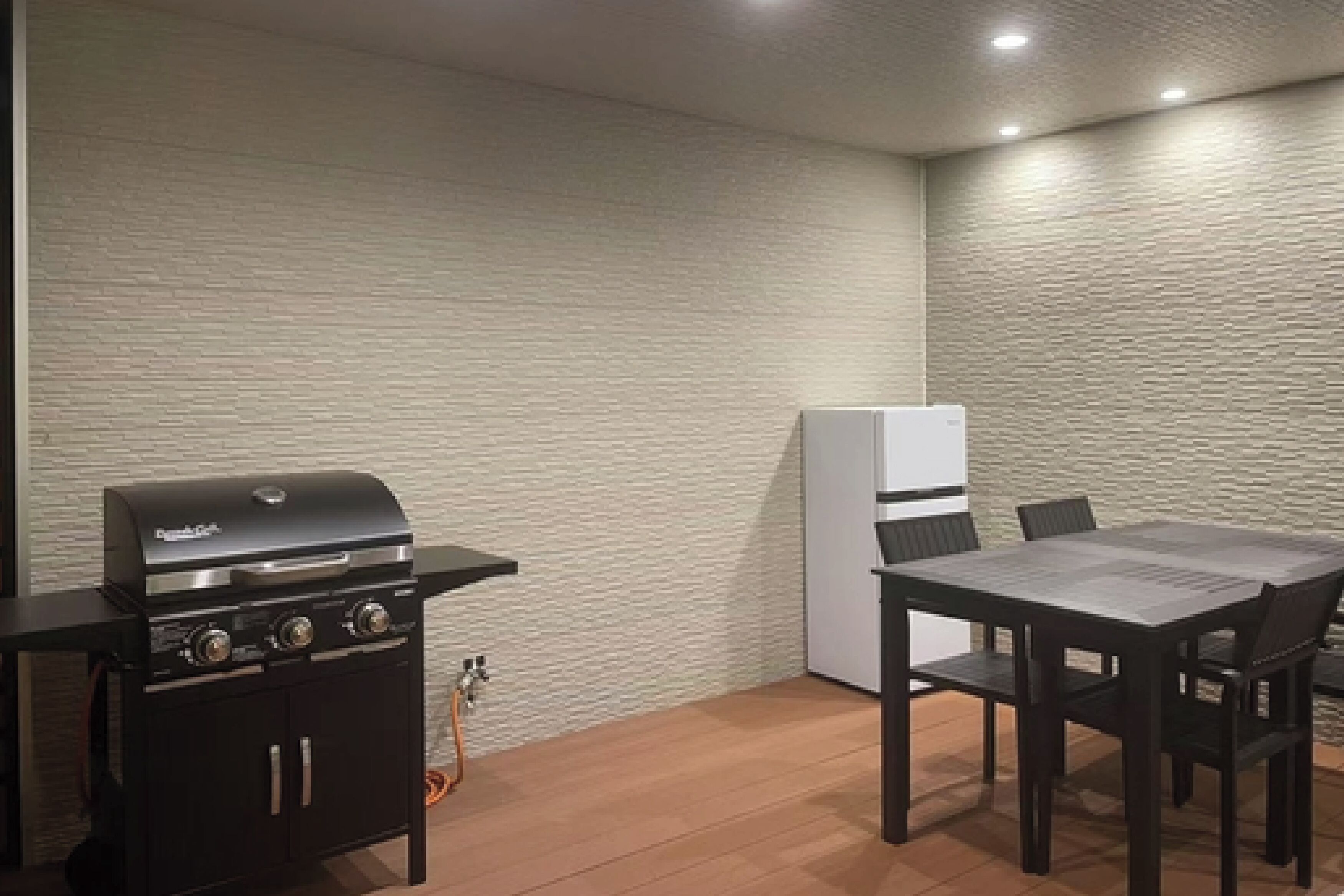 Une cuisine équipée d’un barbecue, d’un réfrigérateur et d’une table à manger avec des chaises.