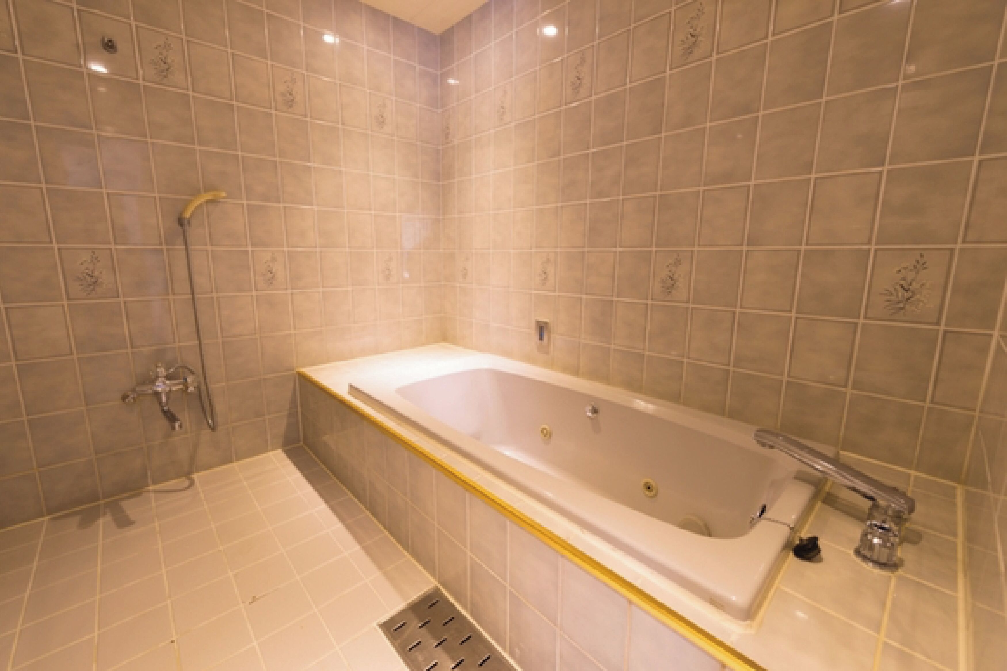 A bathroom with a bathtub, shower, and tiled walls.