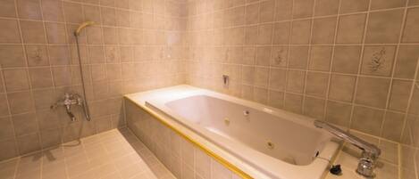 A bathroom with a bathtub, shower, and tiled walls.