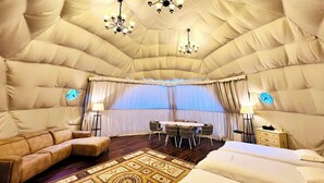 A luxurious room with a large, plush, beige, dome-shaped ceiling, a round dining table with chairs, a sofa, a bed, and two bedside tables with lamps. - Ducale Garden Hotel 99 (Kujukuri)