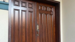 Una puerta doble de madera con pomo de latón, ubicada en un vano con un escalón que la precede.
