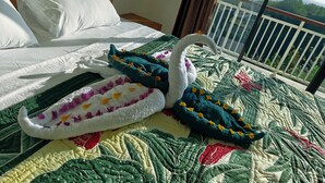 Una cama con una colcha verde y una toalla decorativa con forma de cisne.