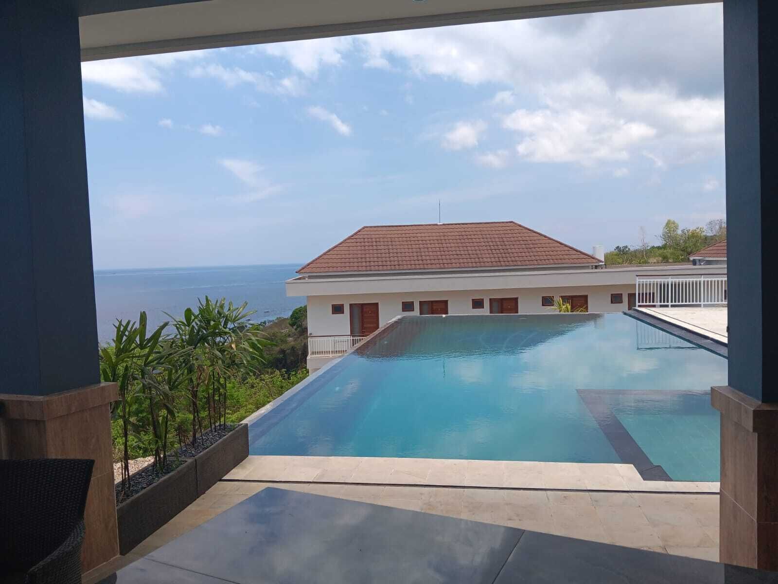 Ein Pool mit Blick auf das Meer und ein Gebäude im Hintergrund.