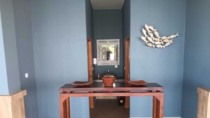 Un pasillo con una mesa de madera, un espejo y decoración mural.