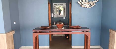 Un pasillo con una mesa de madera, un espejo y decoración mural.