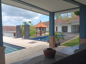 Un espacio al aire libre techado con una piscina, un pabellón y vistas de un edificio residencial.