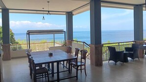Un área de comedor al aire libre, techada, con vistas al océano.