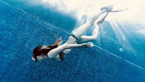 Una persona nada en una piscina con un diseño de cuadrícula en el piso.