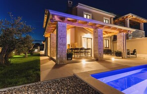 A modern house with a covered patio, a pool, and a well-maintained garden.