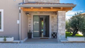 A modern house with a stone facade, a wooden balcony, and a well-maintained garden.