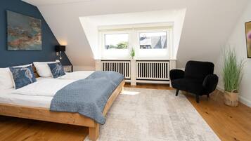 Ein Schlafzimmer mit einem Bett, einem schwarzen Sessel, einer Heizung und einem Fenster.