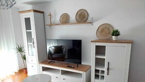 Un salon avec un téléviseur, un meuble en bois et une petite table.