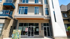 A modern multi-story building with a ground-level entrance, large windows, and a visible first aid room sign.