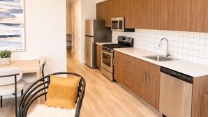 A modern kitchen with wooden cabinets, stainless steel appliances, and a white countertop.
