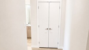 Un couloir doté d’une double porte, de murs aux couleurs claires et d’un plancher en bois.