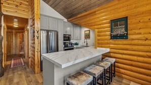A log cabin interior with a kitchen area featuring a marble countertop, stainless steel appliances, and a stone window. - Luxurious 2BDR in Deer Valley with Hot Tub (Park City)