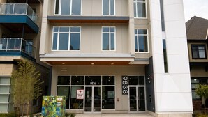Un edificio moderno con entrada a nivel de calle, múltiples ventanas y un cartel que indica un botiquín de primeros auxilios.