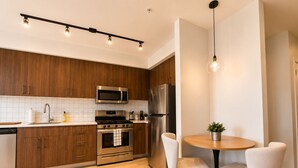 Una cocina moderna con armarios de madera, electrodomésticos de acero inoxidable, una mesa redonda y dos sillas.