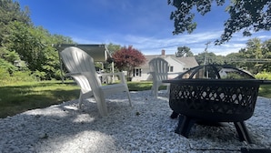 A patio with white plastic chairs and a black grill. - Charming Retreat - Central A/C, Firepit, Walk to Downtown (Falmouth)
