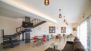 A modern living room with a staircase, a dining area, and a sofa. - Penta Peak By Indostays (Kotagiri)