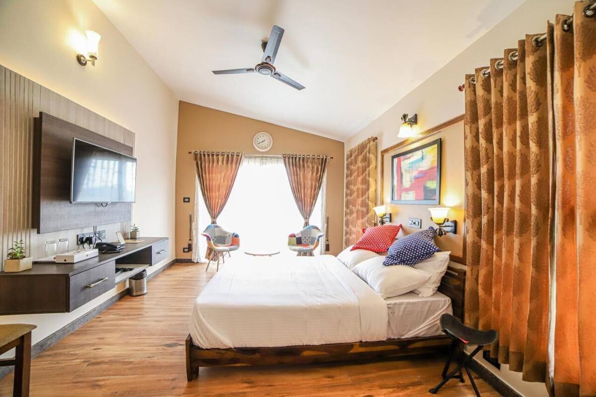 A hotel room with a bed, a desk, a TV, a ceiling fan, and curtains.