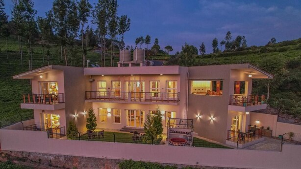 A modern two-story house with multiple balconies, large windows, and a well-lit exterior. - Penta Peak By Indostays (Kotagiri)