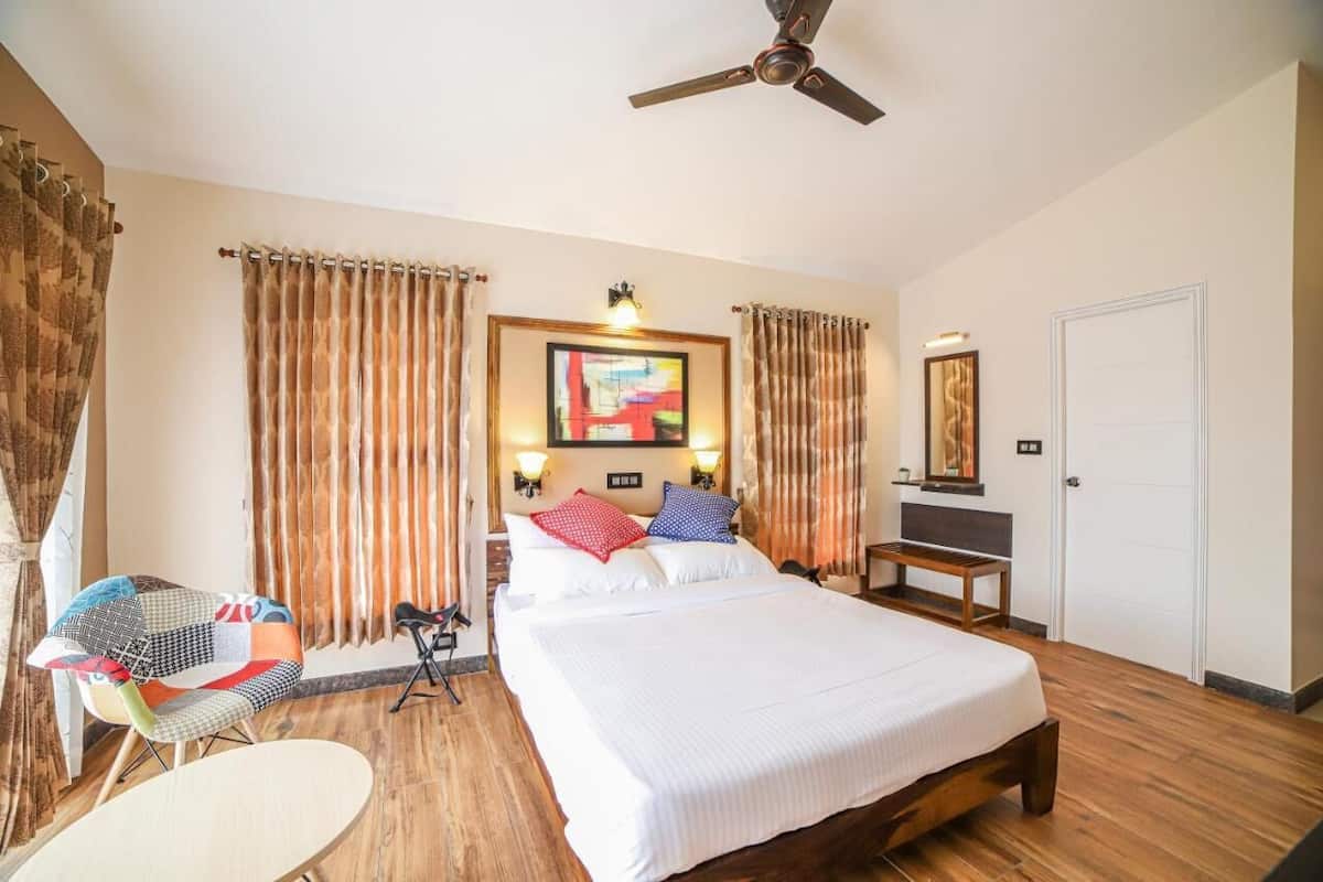 A hotel room with a large bed, a desk, a chair, a ceiling fan, and curtains.