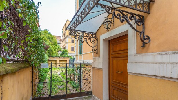 Une ruelle étroite, avec un portail en fer forgé, une porte en bois et un immeuble à la façade jaune.