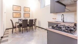 Une cuisine moderne équipée d’une cuisinière à gaz, un coin repas avec quatre chaises et des œuvres d’art encadrées accrochées au mur.