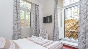 Une chambre à coucher avec un lit, une télévision, une chaise et une fenêtre avec des rideaux.