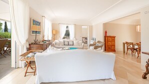 Ein geräumiges Wohnzimmer mit einer großen weißen Couch, einem Holzschrank und einem Essbereich mit Holzsesseln.