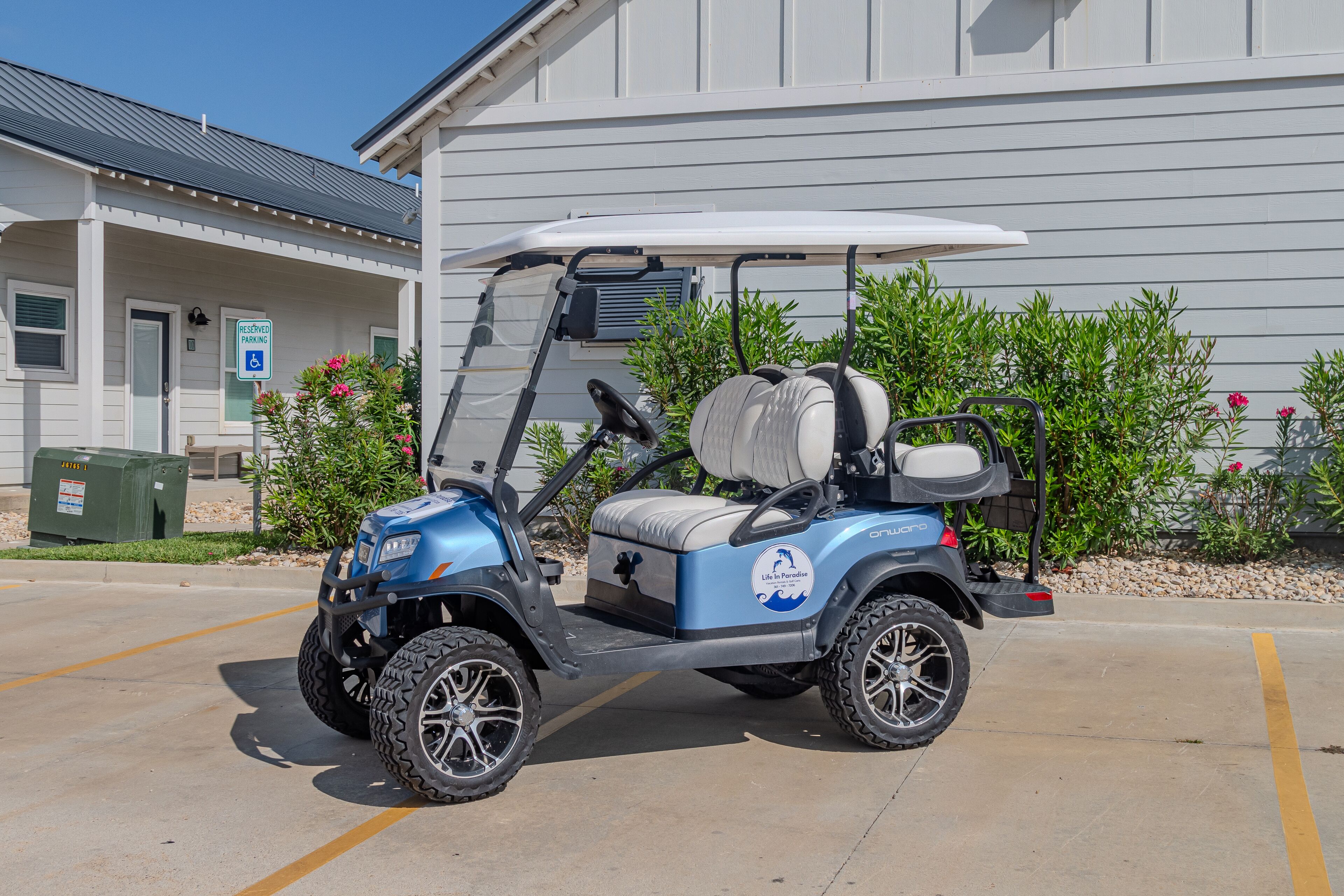 Une voiturette de golf est stationnée dans un espace réservé à cet effet devant un bâtiment, et une pancarte indique qu’il s’agit d’une place de stationnement réservée aux personnes handicapées.