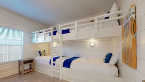 Une chambre avec un lit superposé, un plancher en bois, une petite table et un tableau accroché au mur.