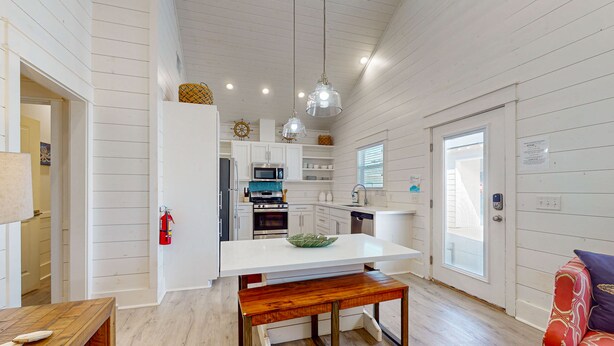 Una cocina moderna con armarios blancos, una isla central e iluminación colgante.