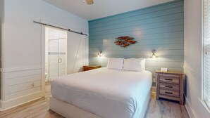 Un dormitorio con una cama grande, un ventilador de techo, una mesita de noche y una lámpara de pared.