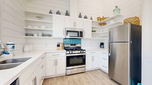 Una cocina moderna con armarios blancos, un refrigerador de acero inoxidable, un microondas y una estufa.
