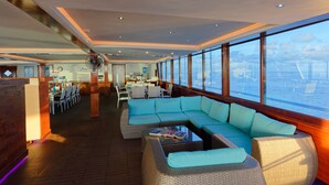 A spacious deck with a large sofa, dining area, and a view of the water. - Yasawa Princess (Malé)