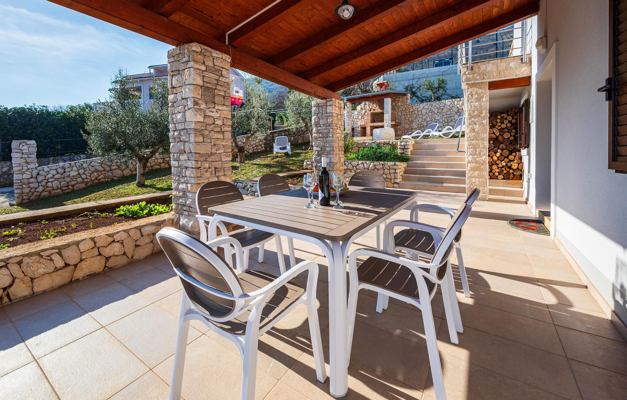 A covered outdoor dining area with stone pillars, a table, and chairs.