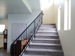 A staircase with a wooden handrail and black balusters leading to a landing. - Villa Calabria (Seattle)