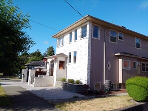 A two-story house with a stone facade, a front porch, and a visible garage. - Villa Calabria (Seattle)
