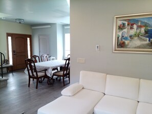 Una habitación con un sofá blanco, una mesa de comedor con sillas y un cuadro en la pared.