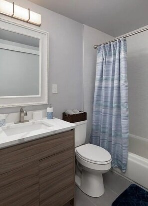 Features a white sink, silver faucet, and a shower area with a striped curtain.