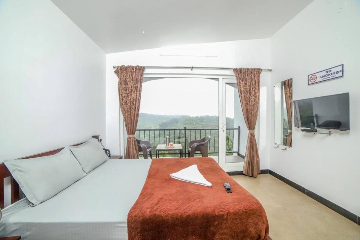 Ein Hotelzimmer mit Bett, Fernseher, einem Balkon mit Blick und einem Rauchverbot-Schild.