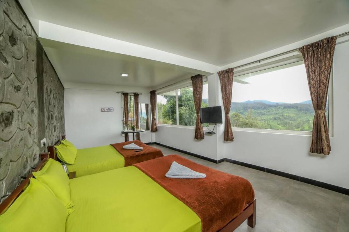 Ein Hotelzimmer mit zwei Betten, einem Fernseher und Blick ins Freie.