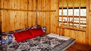 Une pièce de cabane en bois comprenant un lit, une fenêtre avec vue et un plafond en bois.