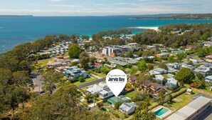 An aerial view of a coastal residential area with houses, a beach, and a clear view of the ocean. - The Gunyah by Experience Jervis Bay (Huskisson)
