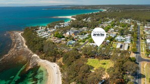 An aerial view of Jervis Bay with a coastal road, beach, and residential area. - The Gunyah by Experience Jervis Bay (Huskisson)
