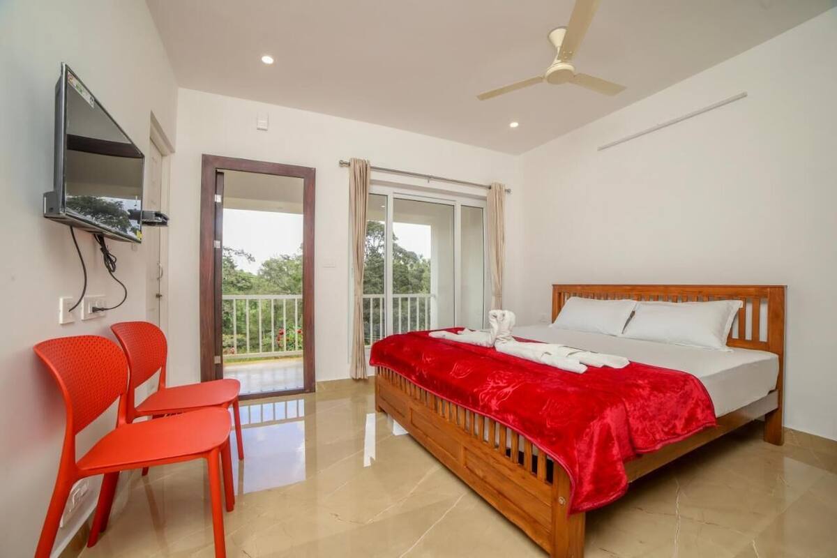 Une chambre à coucher avec un lit, un téléviseur fixé au mur, un balcon avec vue et un ventilateur de plafond.