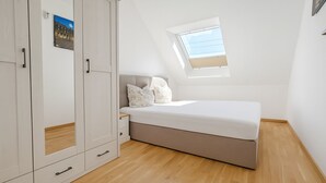 Une chambre à coucher avec un lit, une armoire, un puits de lumière et un plancher en bois.