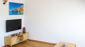 Un salon équipé d’un téléviseur à écran plat, d’un meuble en bois et d’une petite table agrémentée d’objets décoratifs.